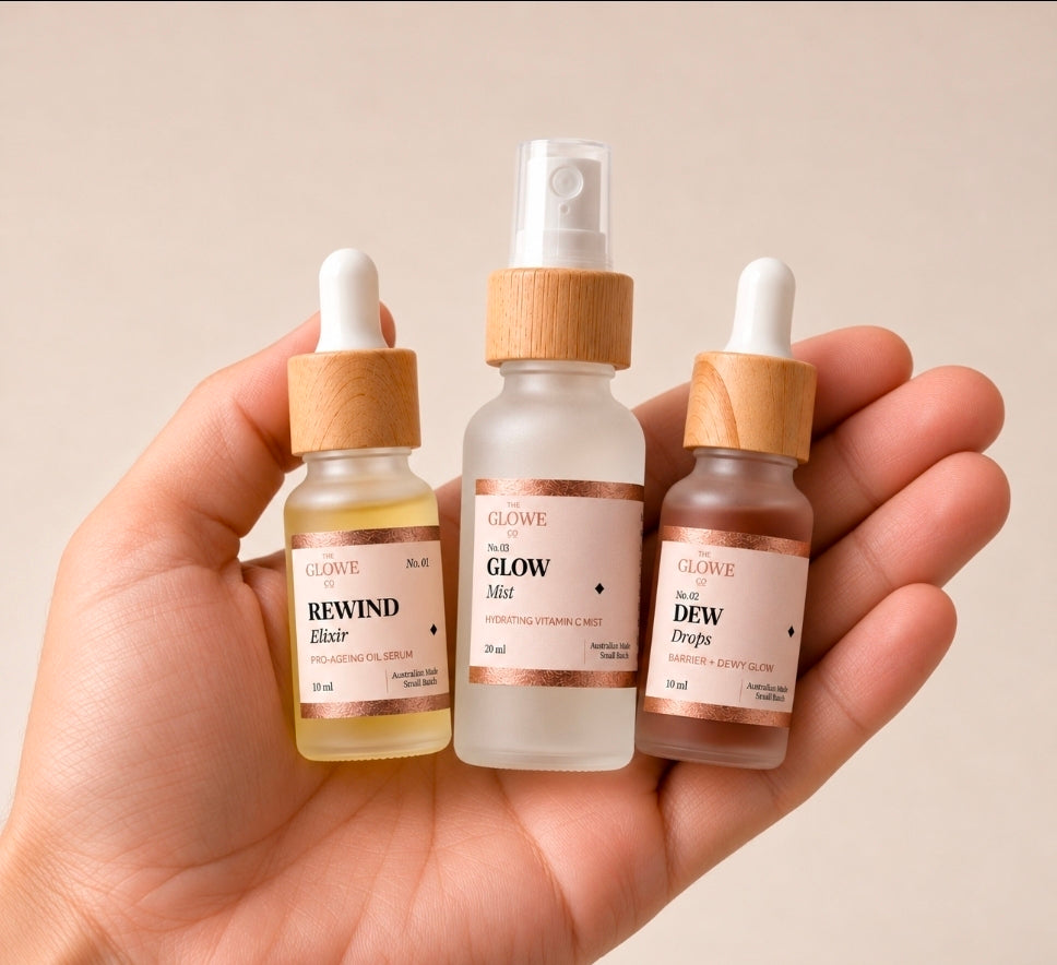 Hand holding The Glowe on the Go travel trio – Rewind Elixir 10 ml, Glow Mist 20 ml and Dew Drops 10 ml in frosted glass with bamboo lids